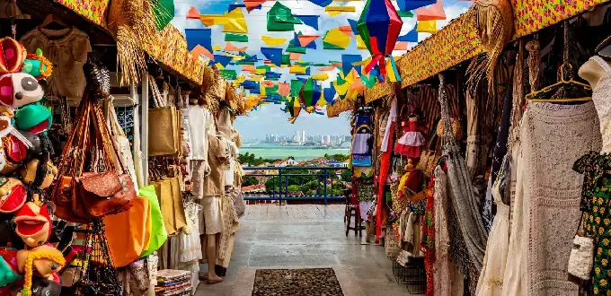 Mercado de artesanías en Olinda, Pernambuco, con coloridos banderines y vista panorámica hacia Recife.