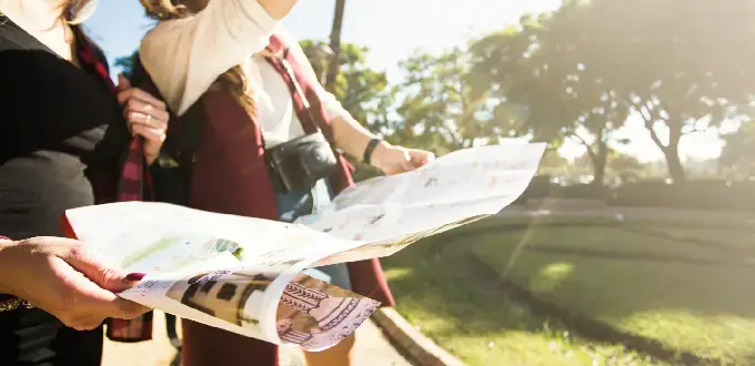 Turistas revisan un mapa mientras caminan por un parque de Ñuñoa, Santiago, explorando la ciudad y sus atractivos.