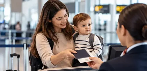Madre con su bebé en brazos entrega documentos de viaje al personal de la aerolínea en el mostrador del aeropuerto.