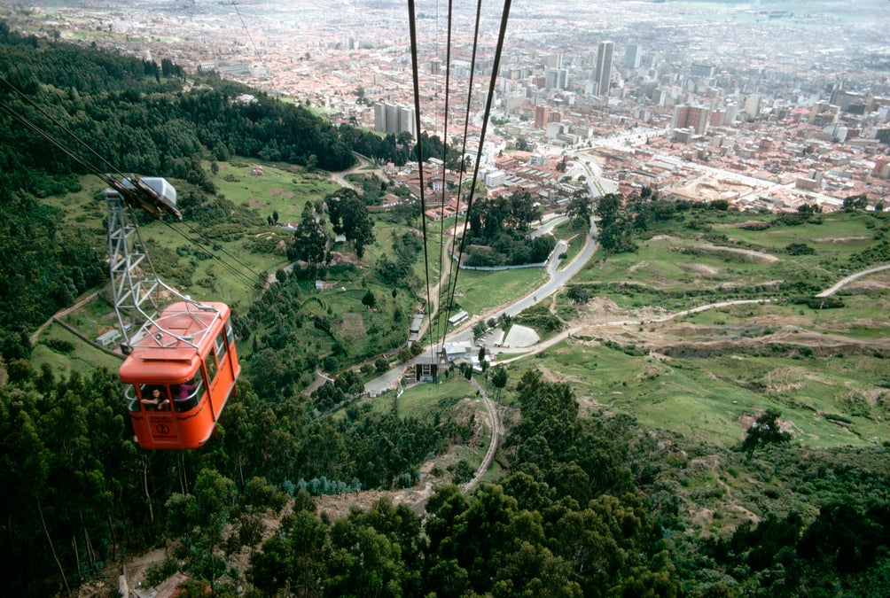 Panorama para glamping: Teleférico de Monserrate ascendiendo sobre las montañas con vista panorámica de Bogotá, Colombia.