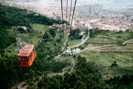 Panorama para glamping: Teleférico de Monserrate ascendiendo sobre las montañas con vista panorámica de Bogotá, Colombia.