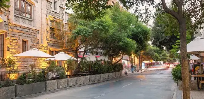 Calle arbolada con restaurantes y terrazas en Barrio Lastarria, Santiago de Chile, zona cultural y gastronómica del centro.