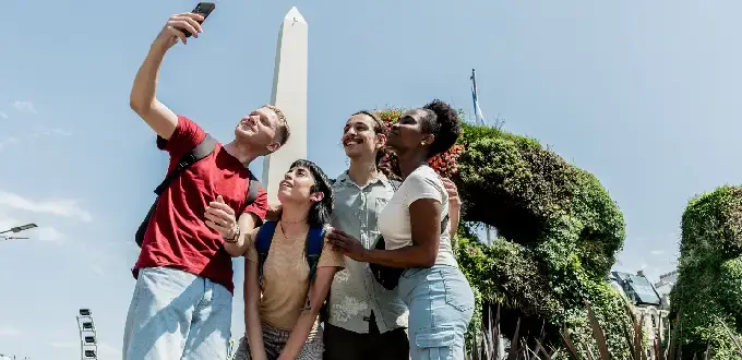 Grupo de amigos tomándose una selfie frente al Obelisco de Buenos Aires.