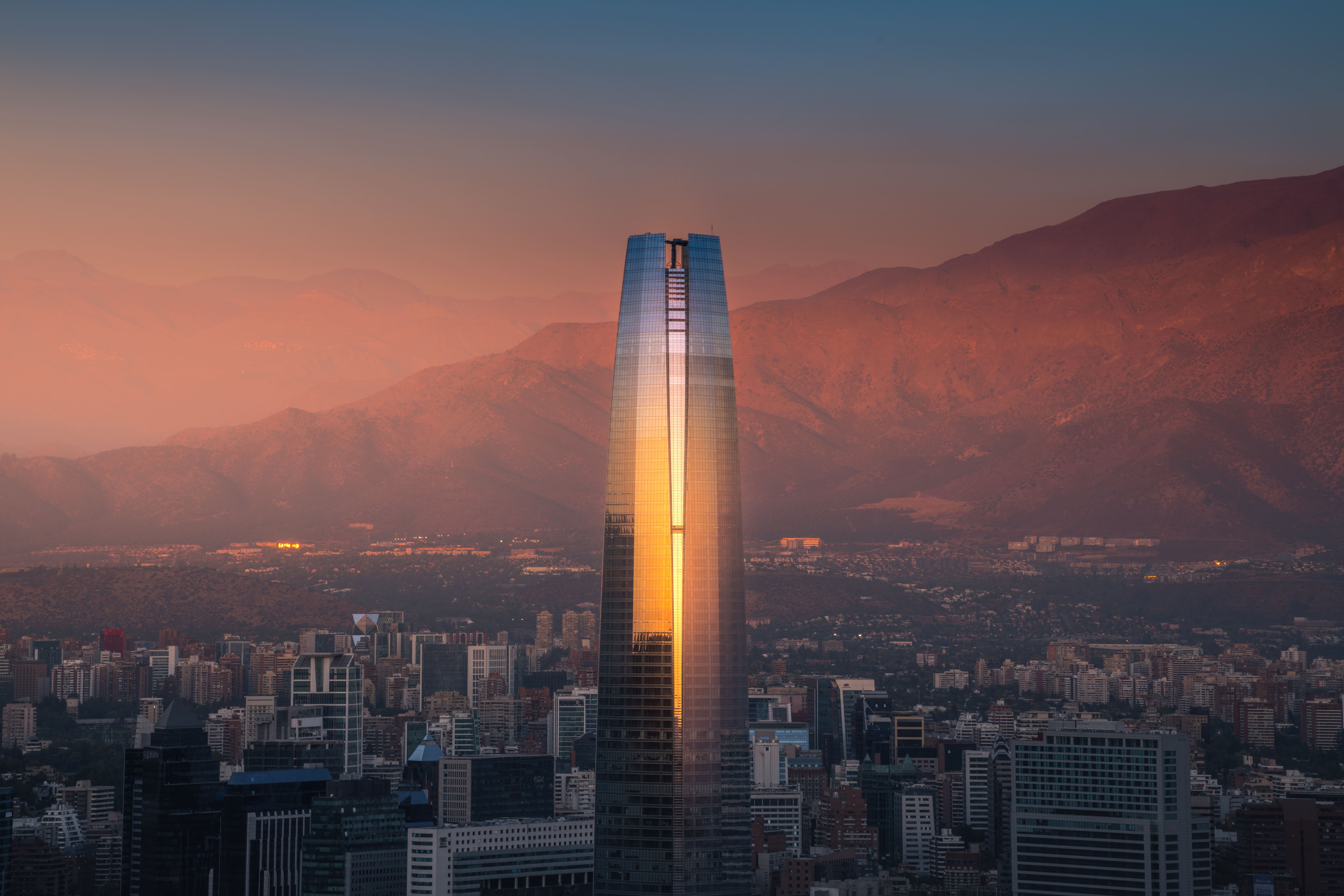 Vista del Costanera Center en Santiago de Chile al atardecer con la cordillera de los Andes de fondo.