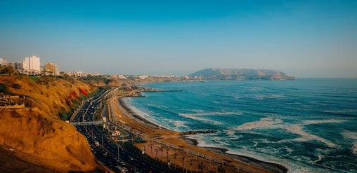 Vista panorámica del malecón de Miraflores en Lima, Perú, con acantilados, edificios y el océano Pacífico al atardecer.