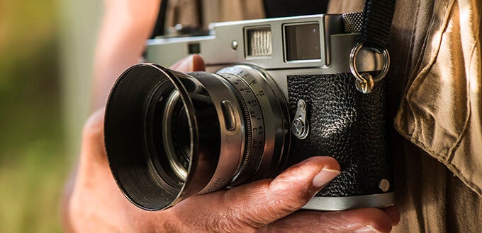 Primer plano de una cámara fotográfica vintage sostenida por un viajero, ideal para capturar cultura, arte y momentos urbanos.