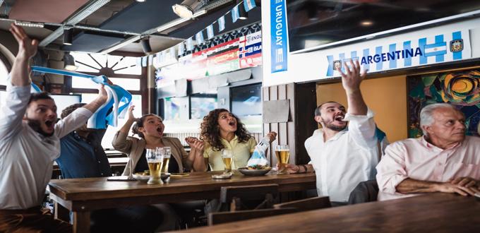 Grupo de personas celebrando un gol en un bar decorado con banderas de Argentina.