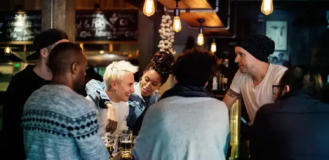 Grupo de amigos comparte en un bar del barrio Bellavista, Santiago, con ambiente nocturno y luces cálidas.