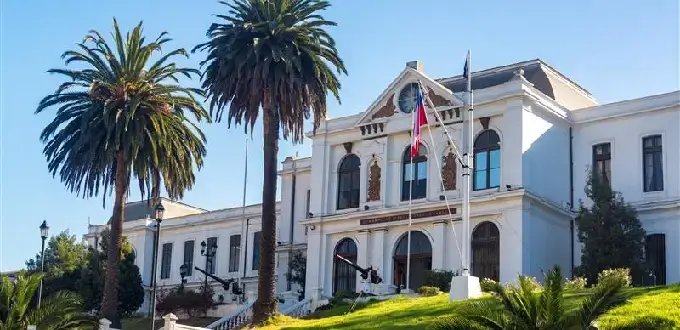 Museo Marítimo Nacional en Valparaíso, Chile, edificio histórico blanco con palmeras y bandera chilena.