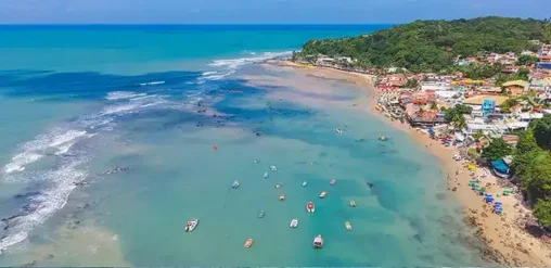 Playa de Pipa en Brasil con aguas turquesas, botes y costa rodeada de vegetación en Rio Grande do Norte.