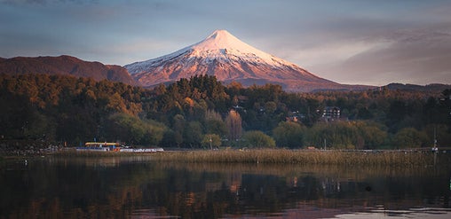 Volcán Villarrica nevado reflejado en el lago al atardecer, paisaje natural de Pucón, Región de La Araucanía, Chile.