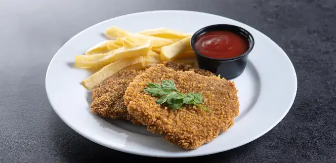 Milanesas argentinas con papas fritas y salsa en plato blanco