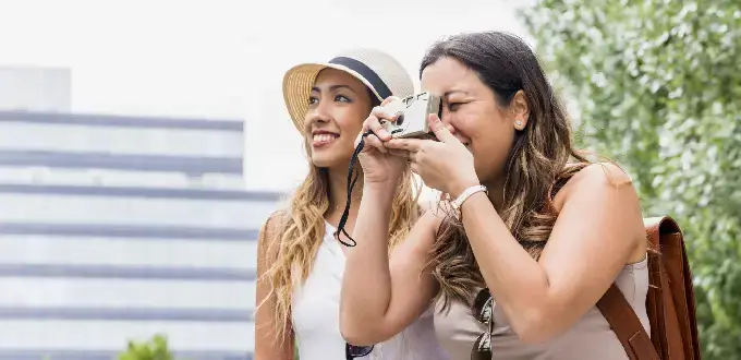 Dos amigas turistas sacando fotos durante un viaje urbano, ideal para contenido de turismo y escapadas.