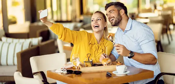Pareja disfrutando gastronomía en un restaurante de Rancagua, Chile, tomando una selfie en un ambiente moderno y acogedor.
