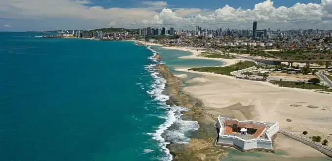 Praia do Forte con mar turquesa, costa rocosa y vista urbana de Natal, Brasil.