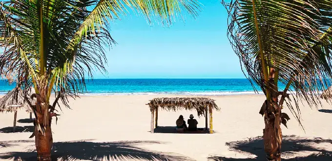 Playa de Máncora en Piura, Perú, con palmeras, arena blanca y vista al océano Pacífico en un ambiente tropical.