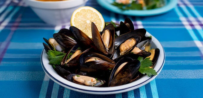 Plato de mejillones al vapor con limón y hierbas frescas, representativo de la gastronomía costera.