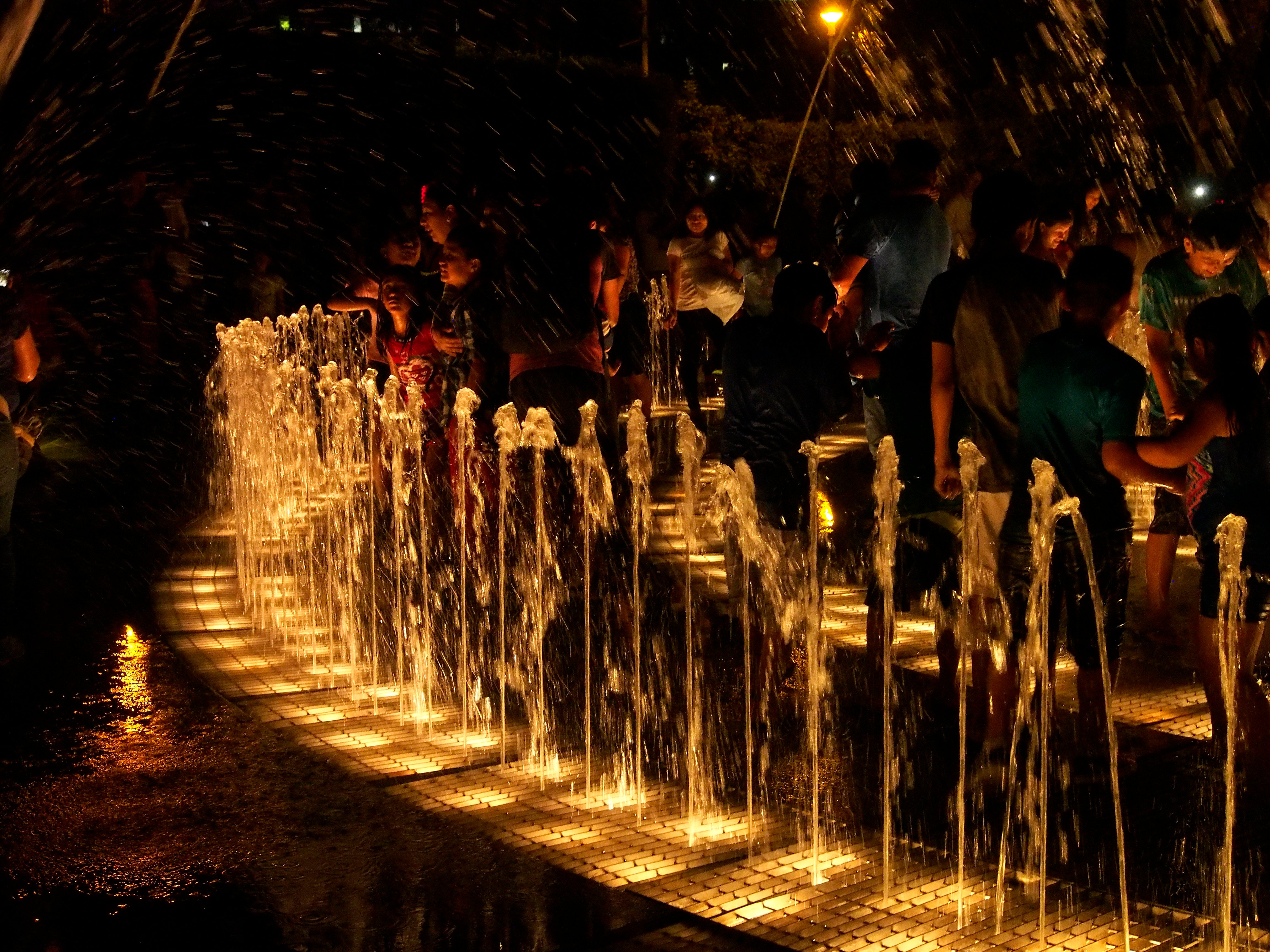 Niños y familias disfrutando las fuentes iluminadas del Circuito Mágico del Agua en Lima, Perú, durante la noche.