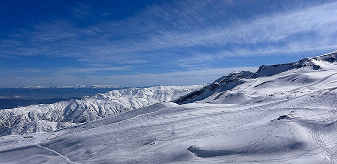 Panorámica de montañas cubiertas de nieve y pistas invernales, paisaje de alta cordillera en Farellones, Región Metropolitana, Chile.