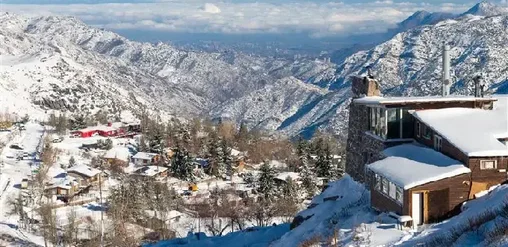 Pueblo de Farellones en la cordillera de los Andes cerca de Santiago, con casas de montaña cubiertas de nieve y valle al fondo.