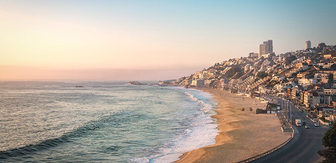 Vista costera de Playa Reñaca con edificios sobre los cerros y el océano Pacífico al atardecer, destino turístico de Viña del Mar, Chile.