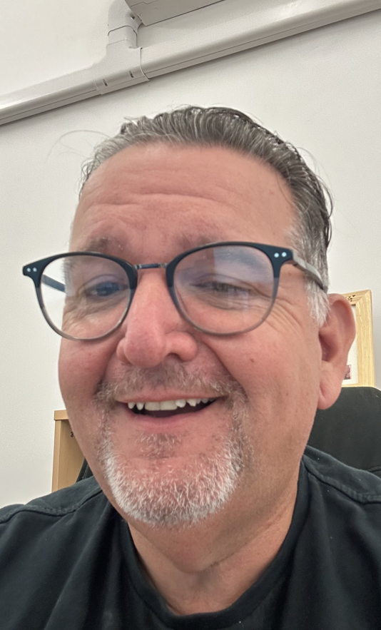 A profile picture of a man wearing glasses, wearing black