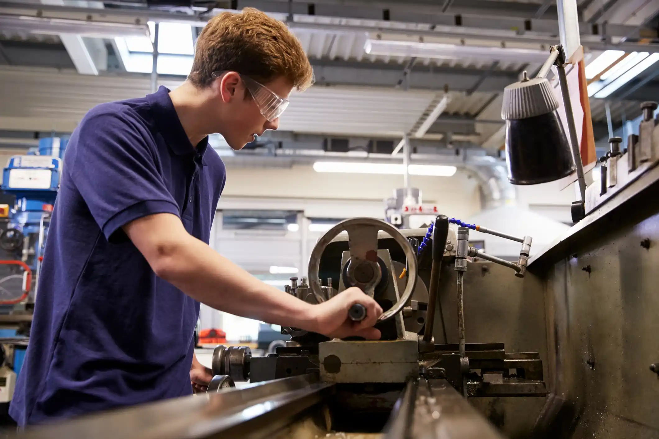 Young mechanical worker uses lathe in workshop