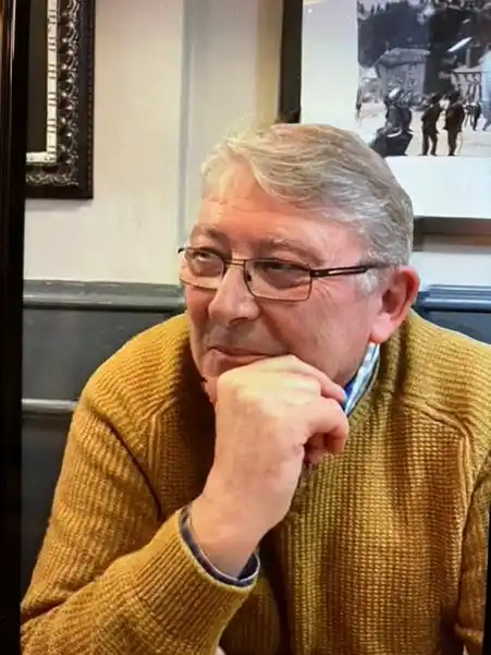 Profile picture of a man wearing glasses and a mustard jumper