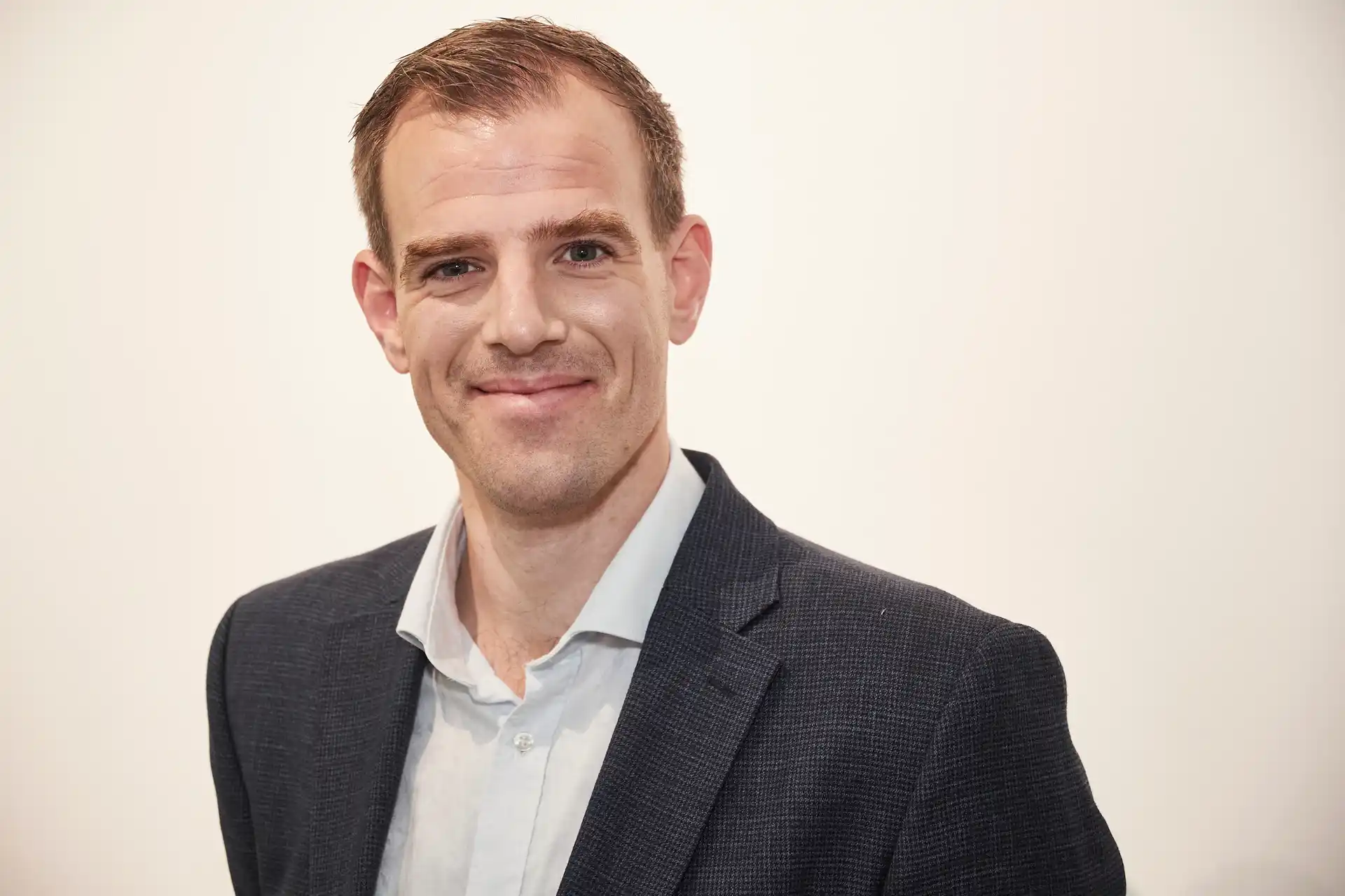 A headshot photograph of a man wearing black and white