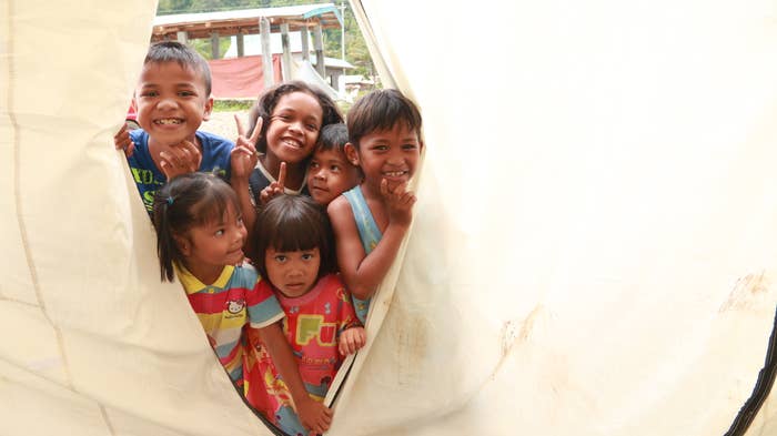 A group of boys and girls standing at the entrance of a tent.