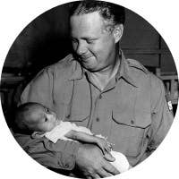 Bob Pierce carrying a little girl in his arms.