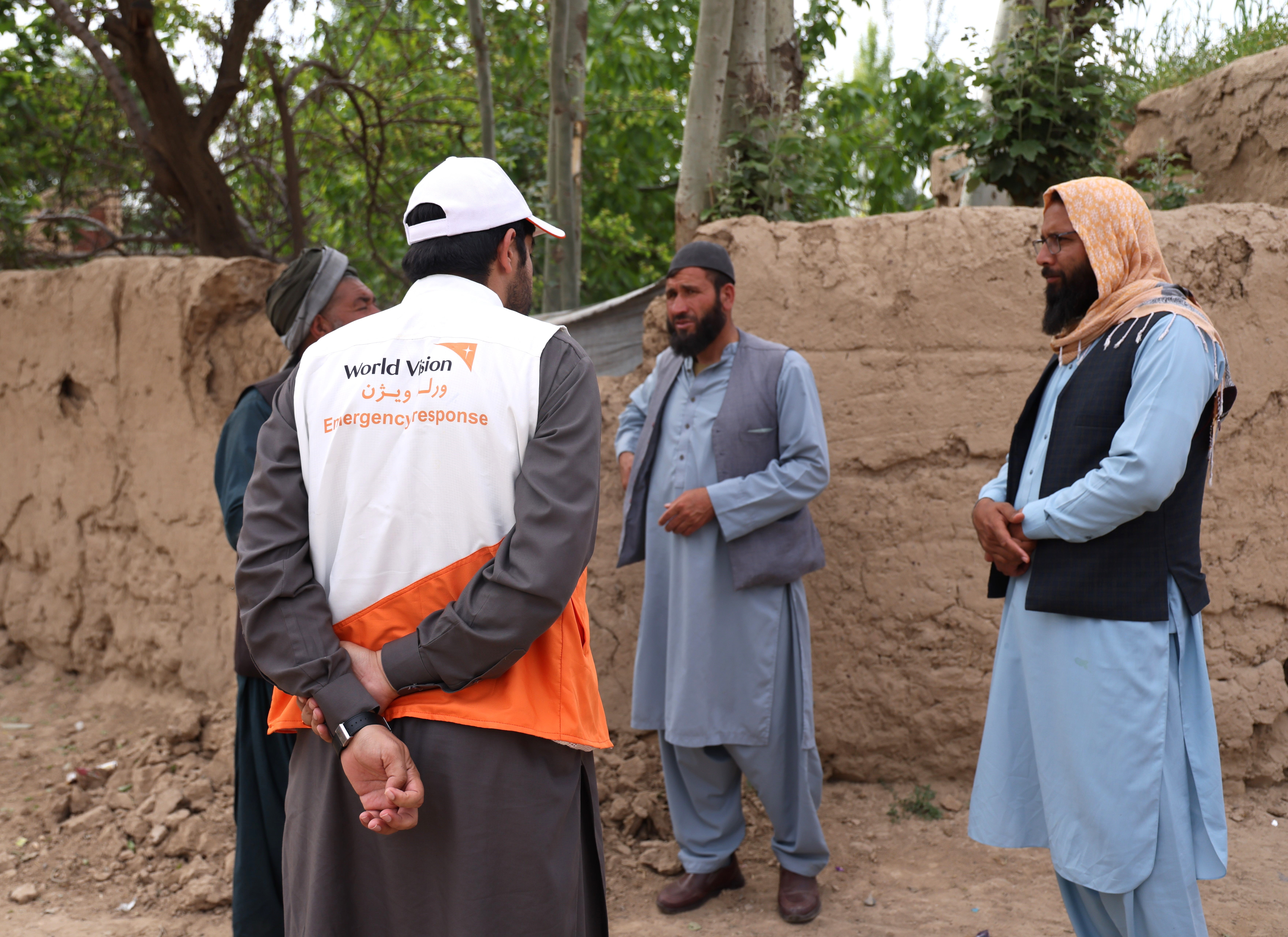 Afghan men stand in a circle discussing the plans for a new water source project