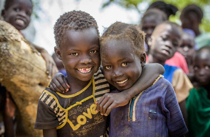 Two children smiling with their arms around each other.