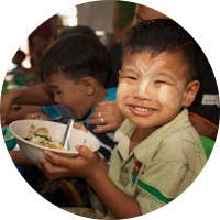 A child happily eating a bowl of food.