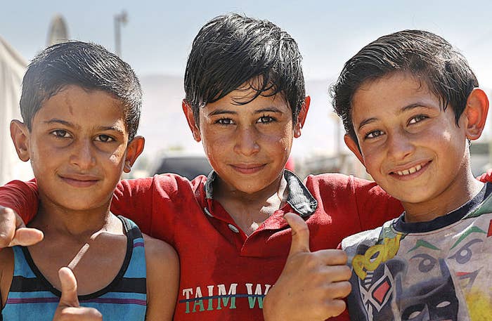 Three boys standing next to each other. The boy in the middle has his arms around the two other kids.