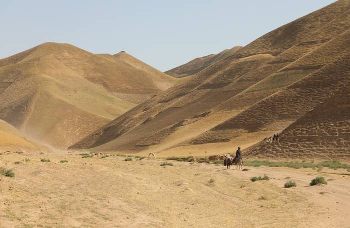 Two people walking in a vast expanse of desert. 
