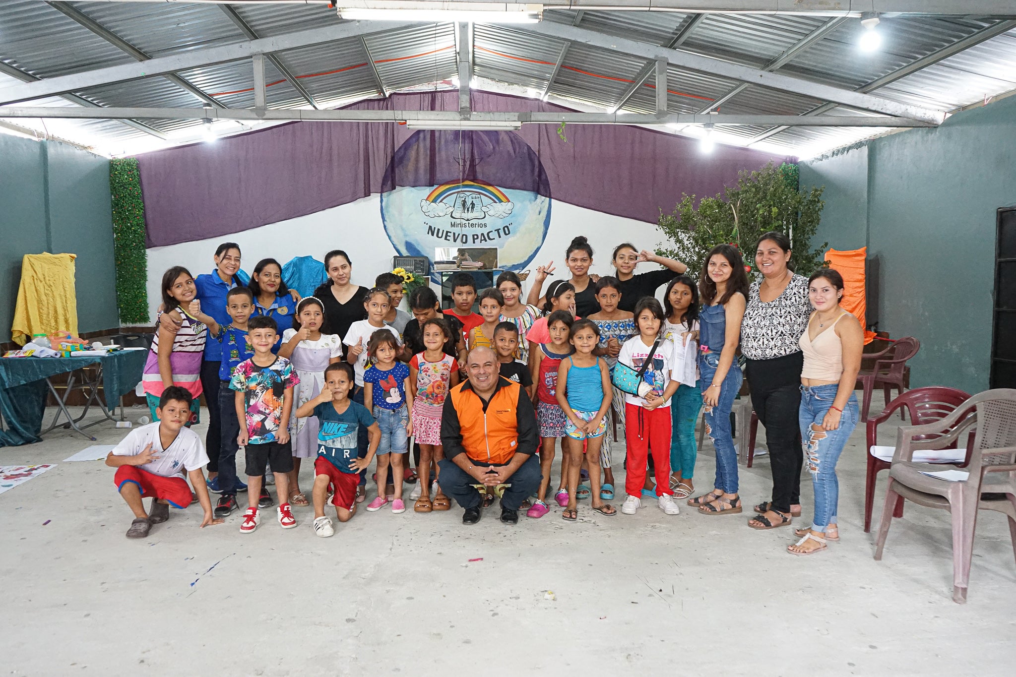 A big group of smiling children and young people stand together at the end of a painting class
