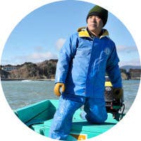 A man wearing a blue padded jacket riding a boat.