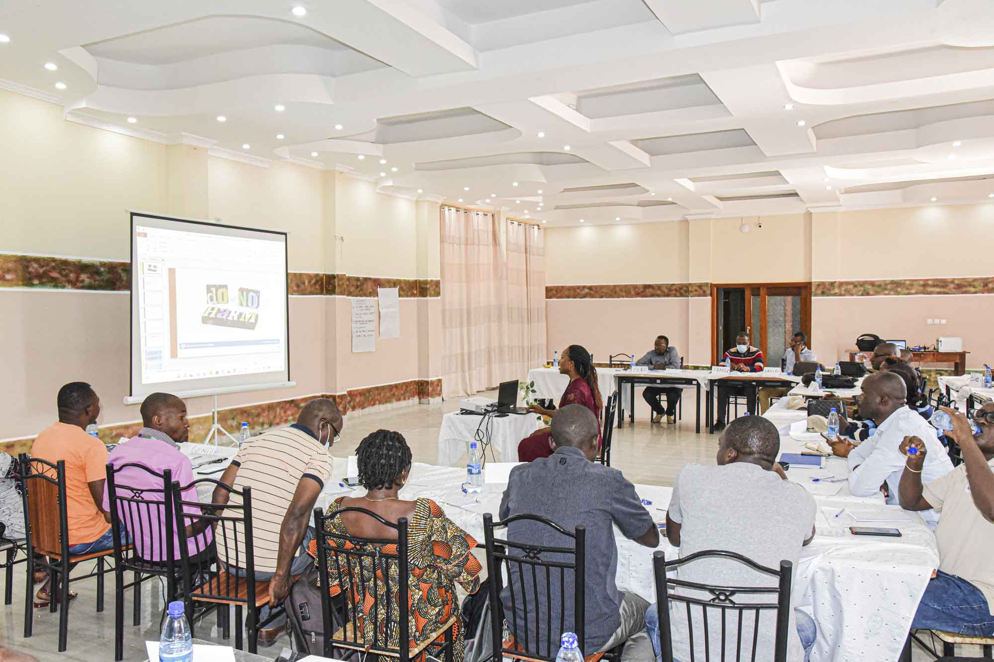 A World Vision event is being hosted in a large meeting venue. Attendees are seated at tables, while a presentation is given on a large screen.