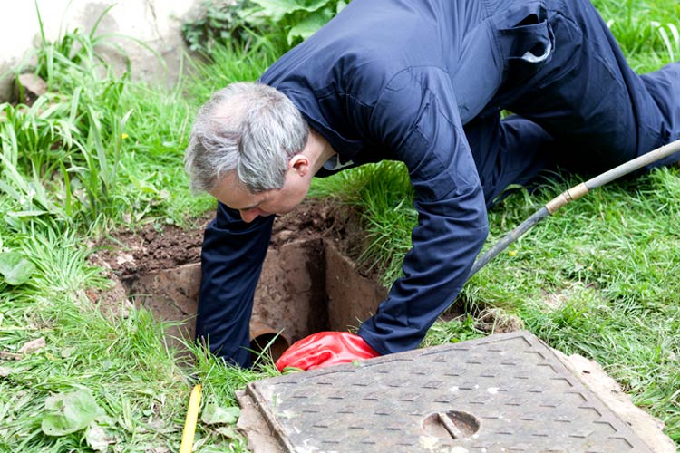 Man fixing outdoor broken sewage pipe. Who's responsible for busted sewage lines in Tennessee?