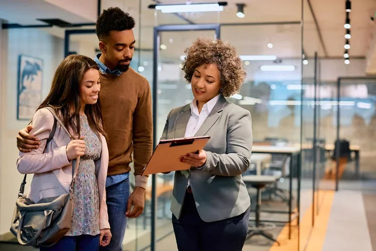 Couple and independent insurance agent going through paperwork in the office. Pros and cons of using an independent insurance agent.