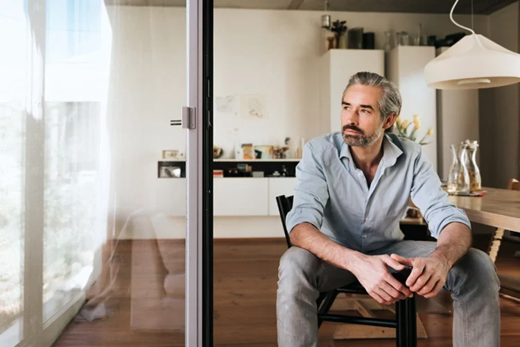 Pensive man looking out of the window. Are You Over-insured?