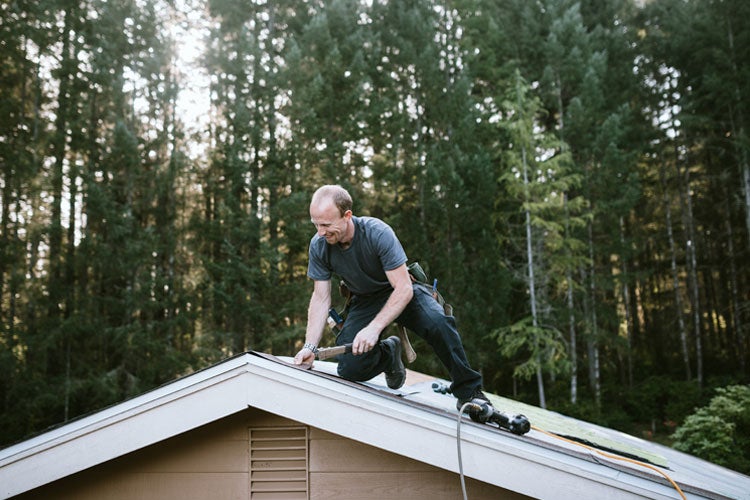 A roofing contractor works on putting in new roofing shingles. How to protect yourself from roofing scams in South Carolina. 