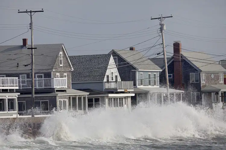 Ocean Storm Waves Crashing into Seawall in front of Houses. Do Houses With Basements that Flood Cost More to Insure?