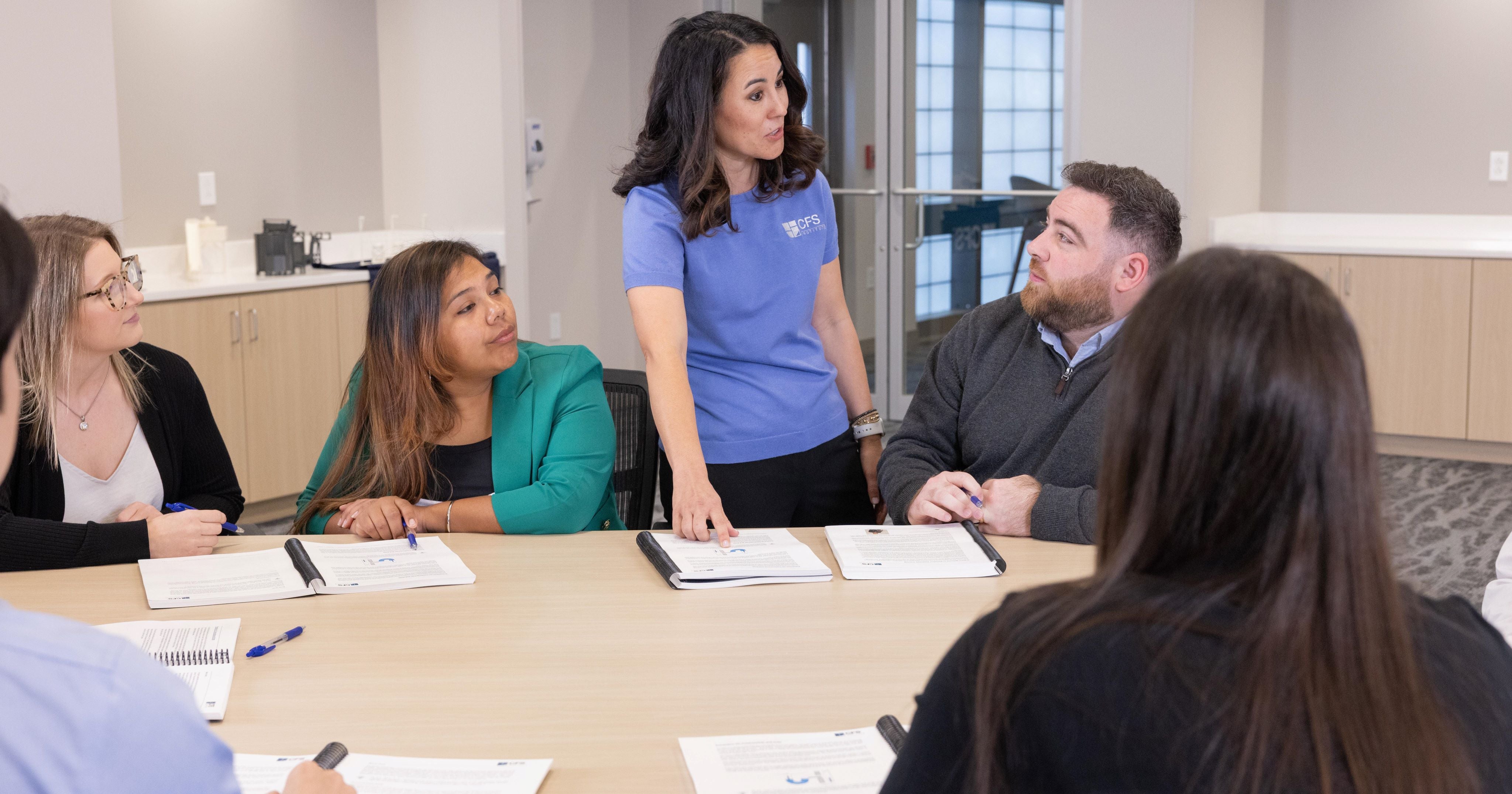 Female trainer explaining something to a participant at the table in the classroom