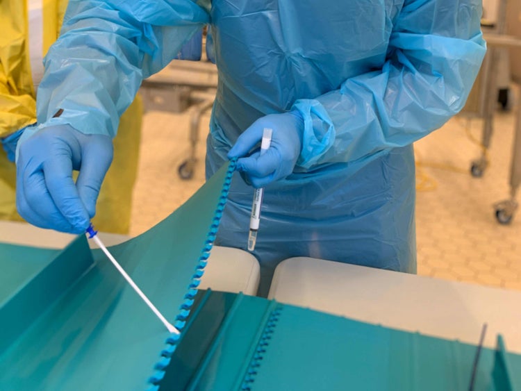 Person in blue personal protective equipment sampling or swabbing a ThermoDrive conveyor belt. 