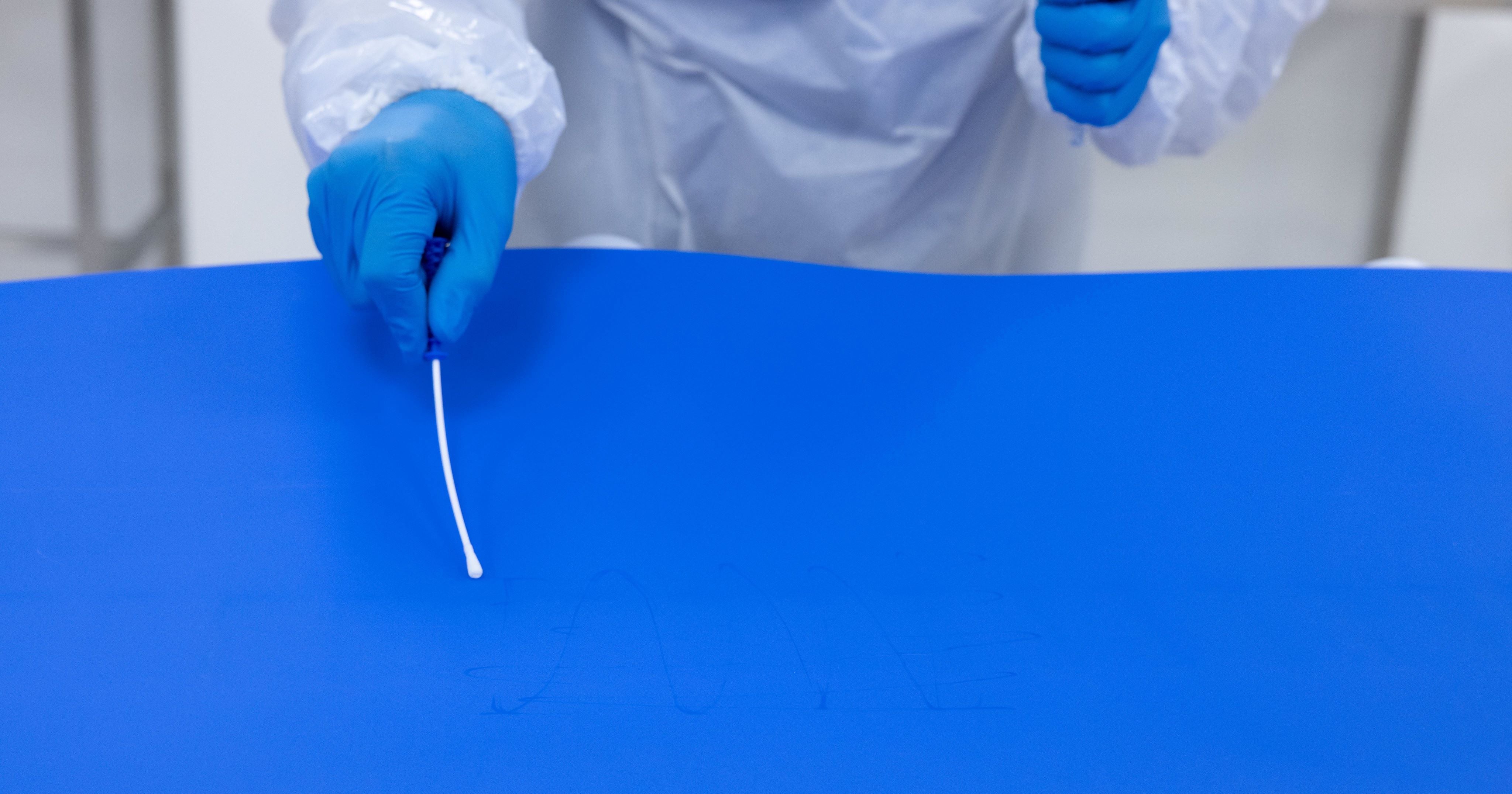 Gloved hand taking a sterile sampling swab on a blue ThermoDrive belt