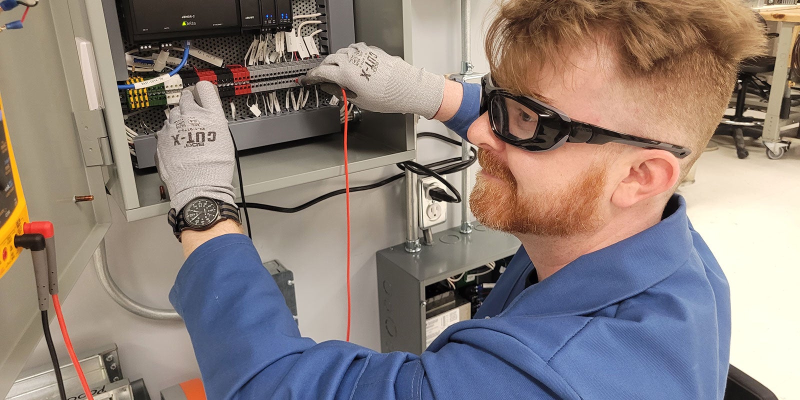 A man wearing safety goggles working in an electrical panel