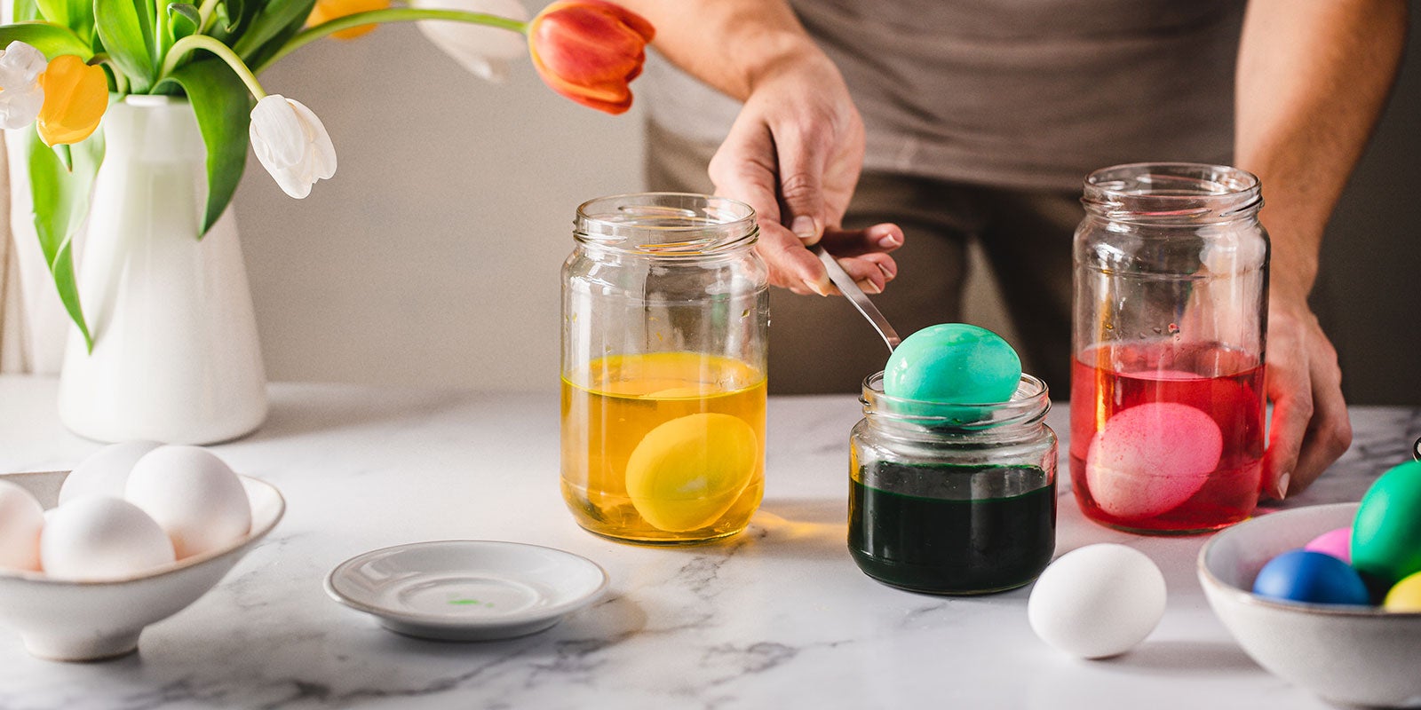 A person painting eggs in a jar