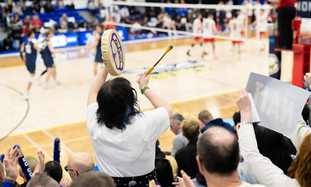 A person holding a stick and a shield in front of a crowd